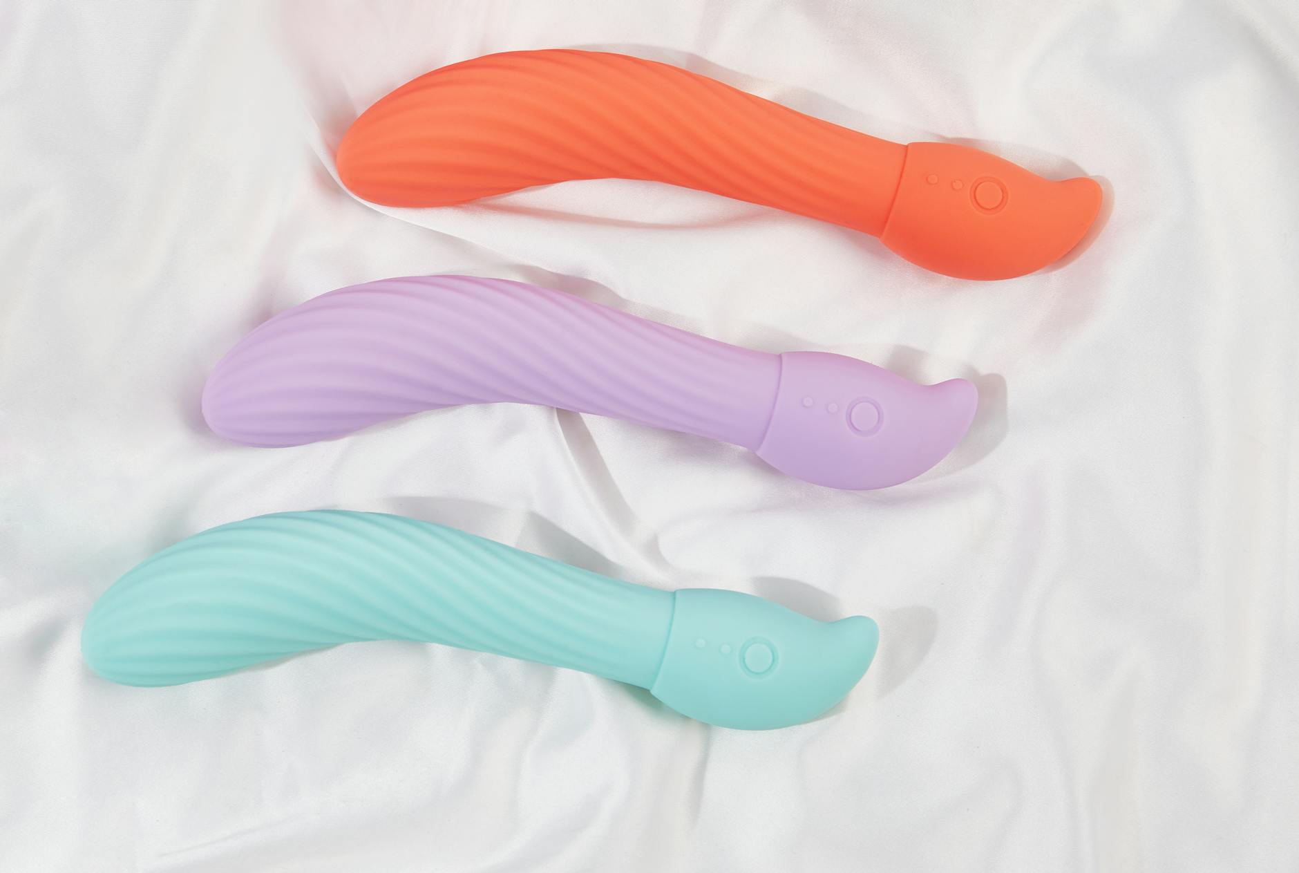 Three colorful silicone vibrators displayed on white fabric, showing smooth design and texture.