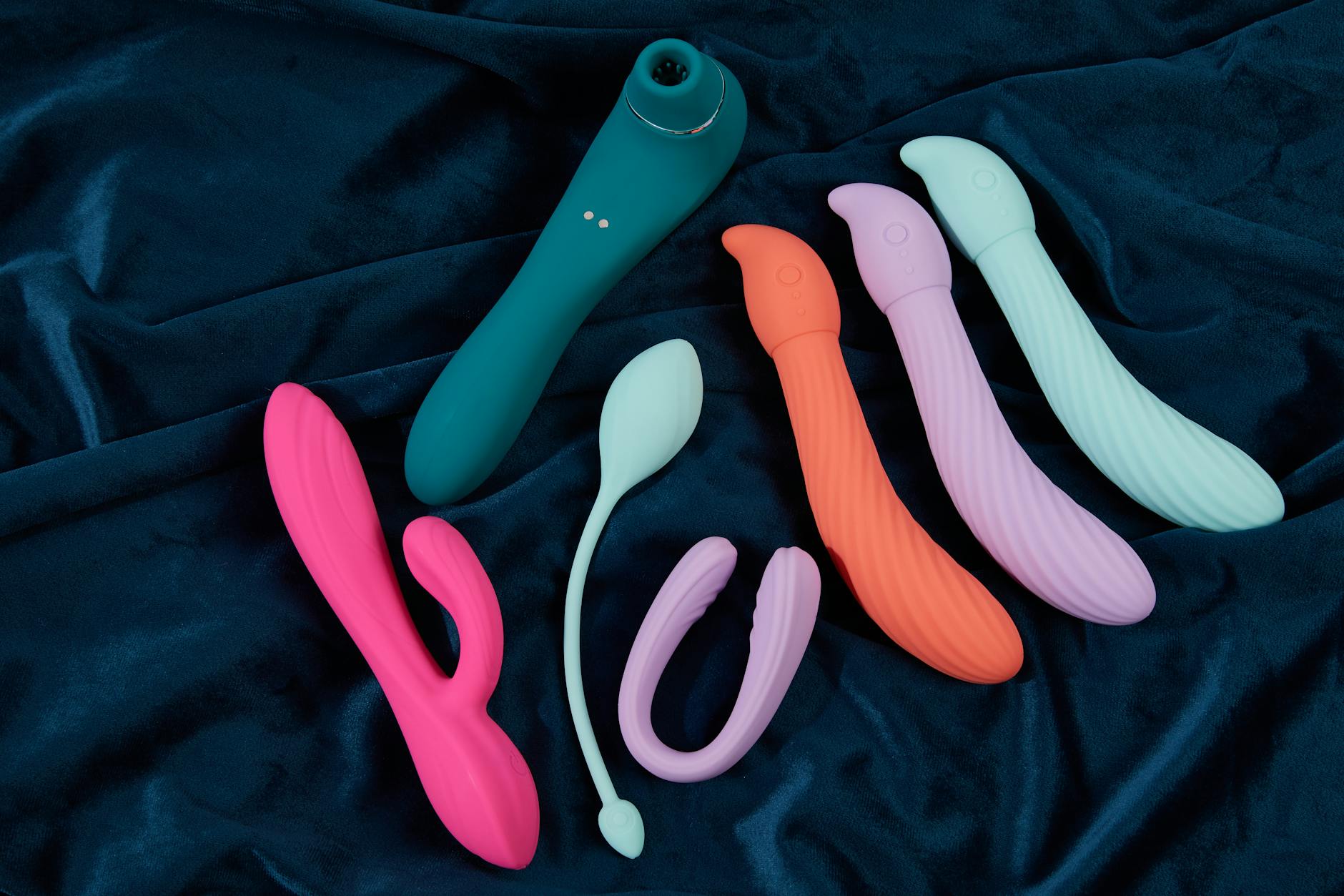 Vibrant display of silicone sex toys on dark blue fabric, showcasing lemon vibrators and other designs