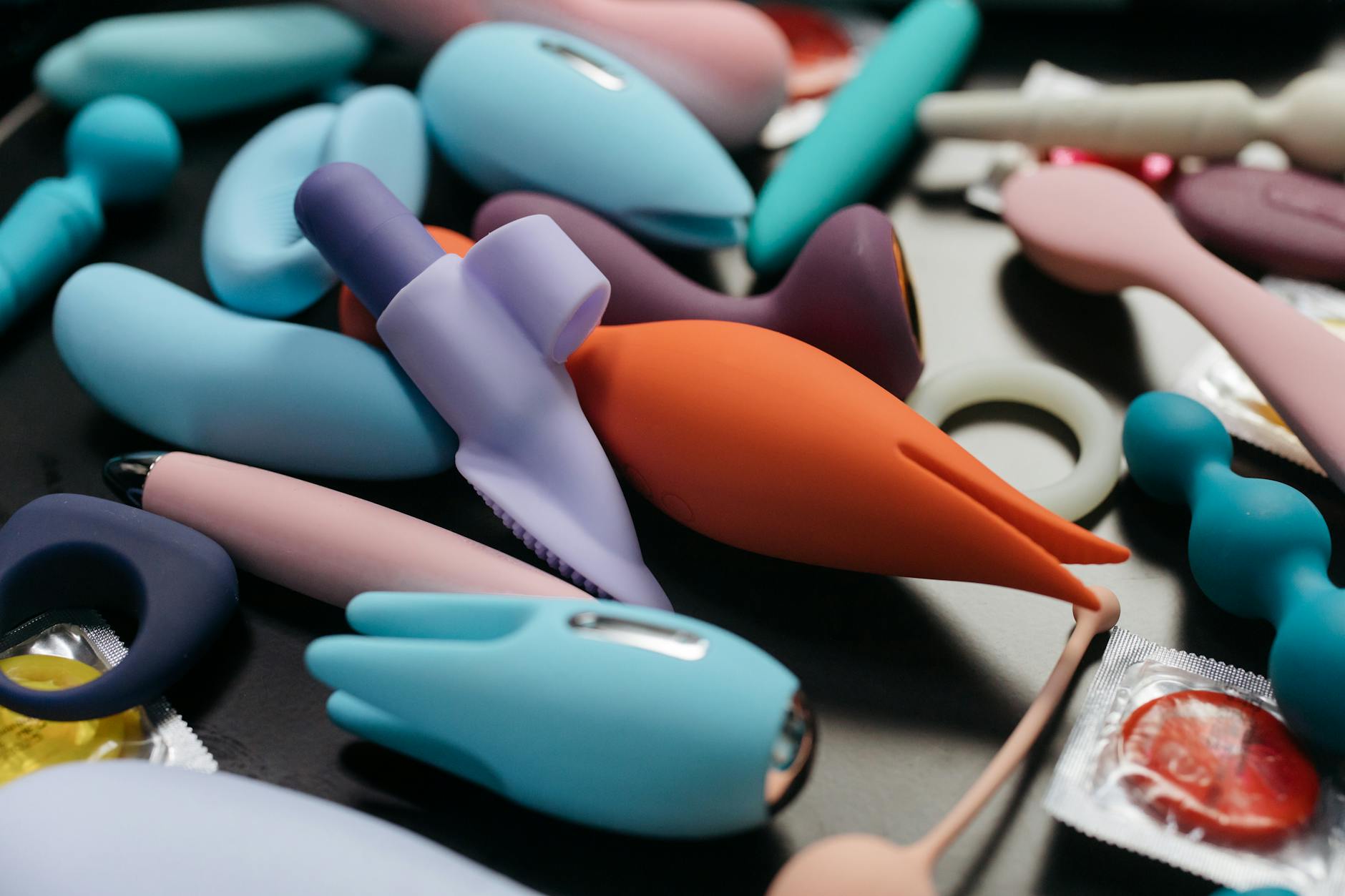 Two hands holding a pink and blue silicone vibrator against a pastel background