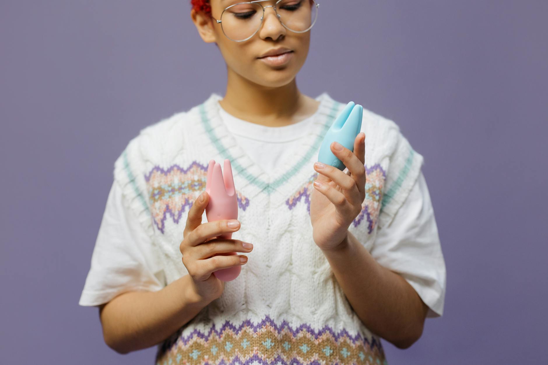 Woman holding a blue and pink silicone vibrator while considering how to introduce toys to a new partner.