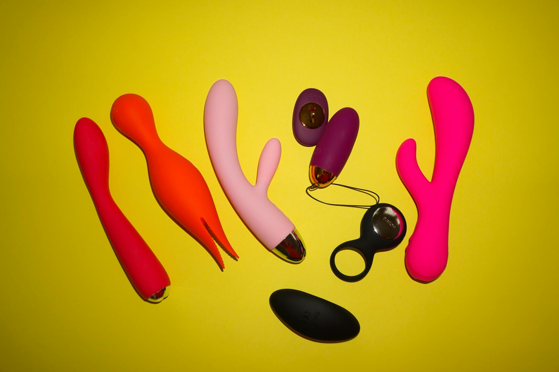 Blue silicone vibrator held in hand against purple background, representing clitoral pleasure and self-care